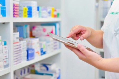 Pharmacist holding computer tablet in pharmacy drugstore